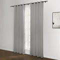 Two grey grommet top curtains on a black rod frame a window with natural light in a room with dark wood flooring and a white wall displaying an abstract black and white framed artwork