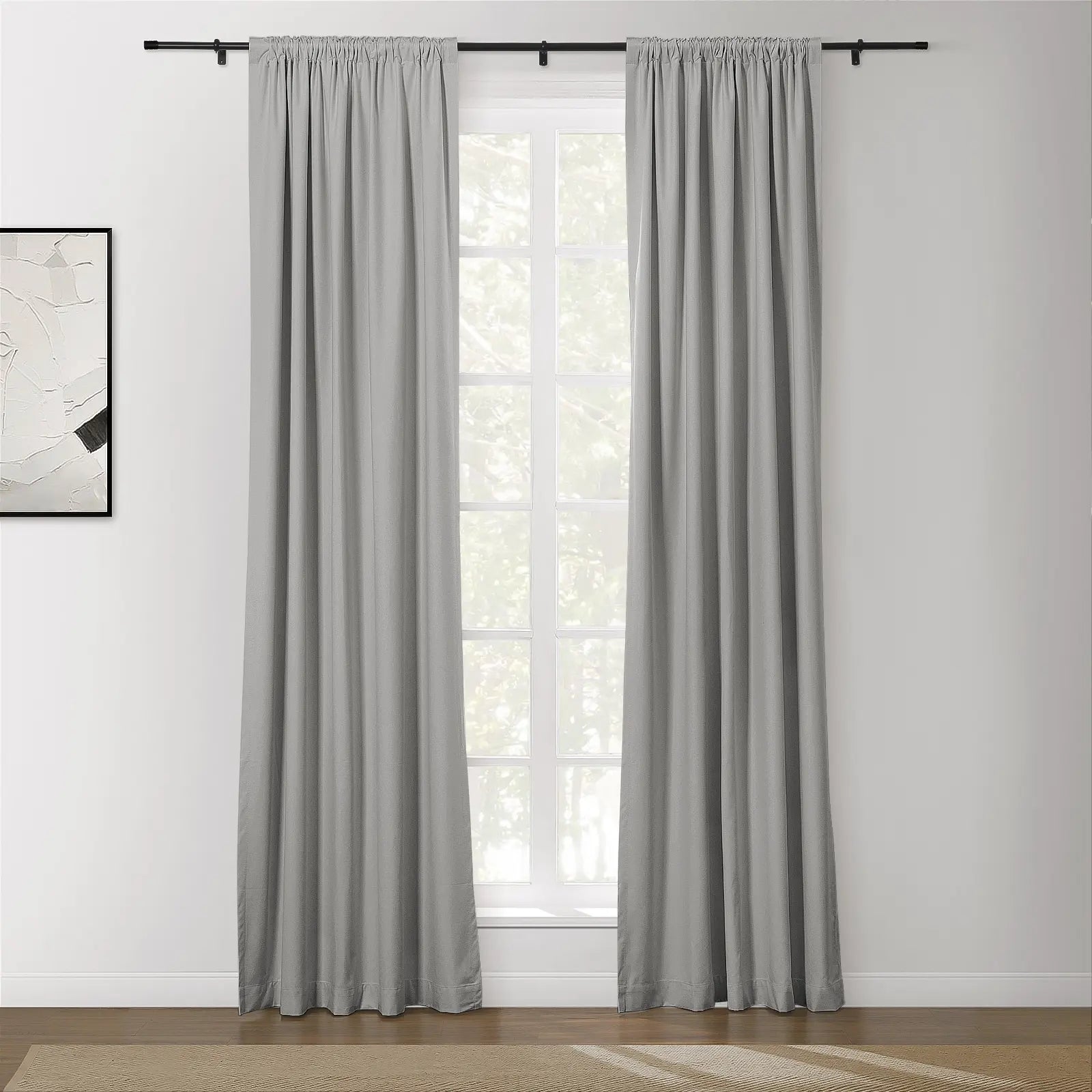 Medium gray rod-pocket curtains on a black rod over a white multi-pane window with an abstract artwork on the adjacent wall and a beige rug on the floor