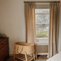 Light Khaki Liz Linen Pleated Curtains in a bedroom beside a rattan bassinet and wooden chest