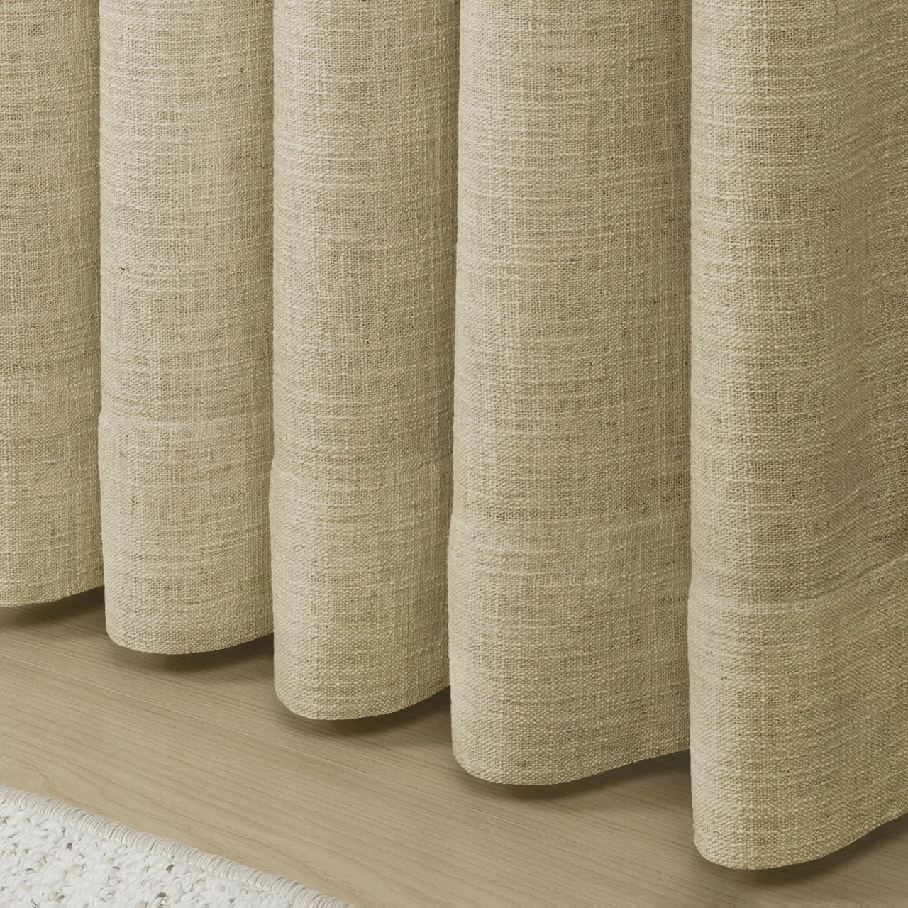 Light Khaki Liz Linen Pleated Curtains rounded curtain hems above a pale wood floor