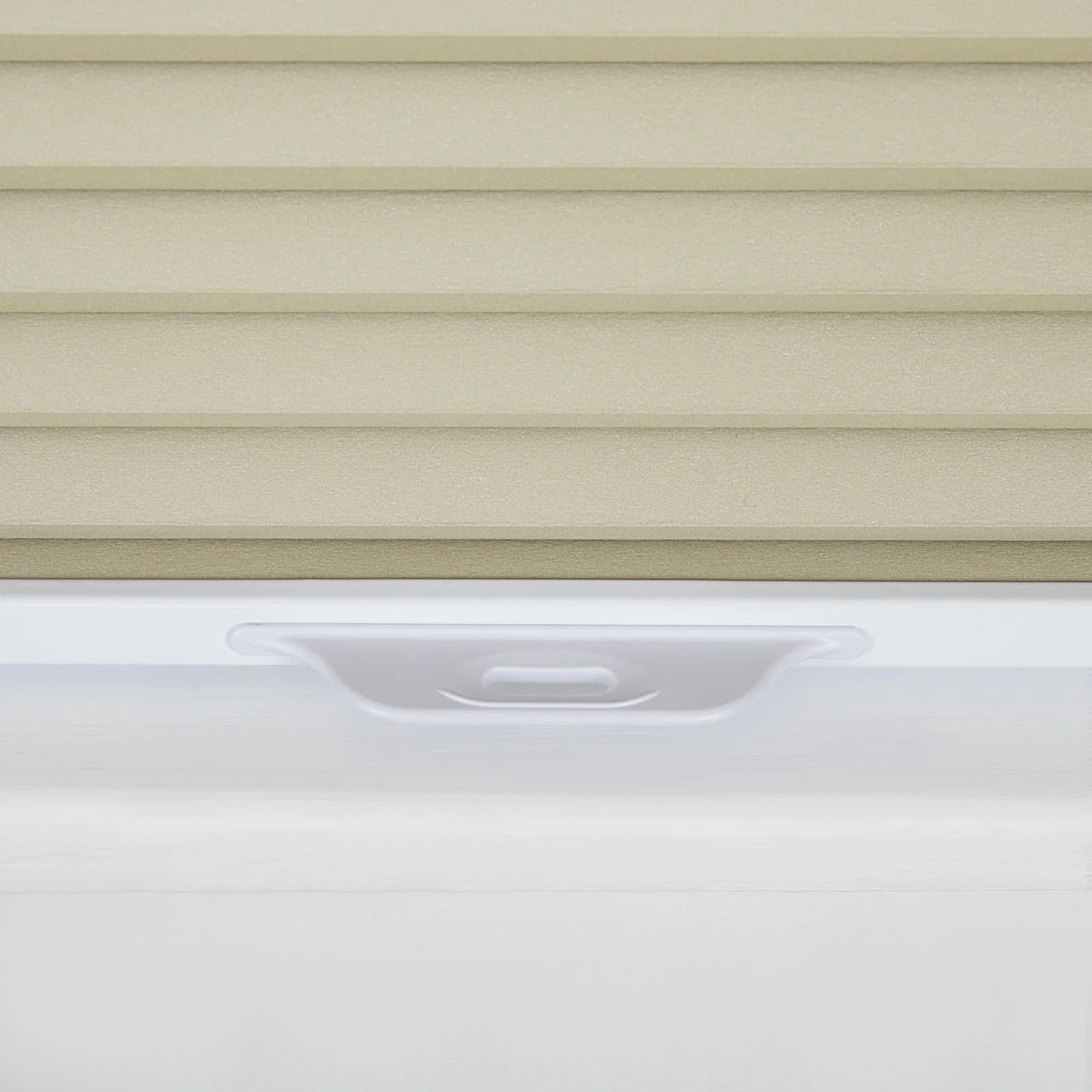 Photograph of textured beige horizontal window Blinds above a smooth white window frame featuring a subtle recessed pull handle
