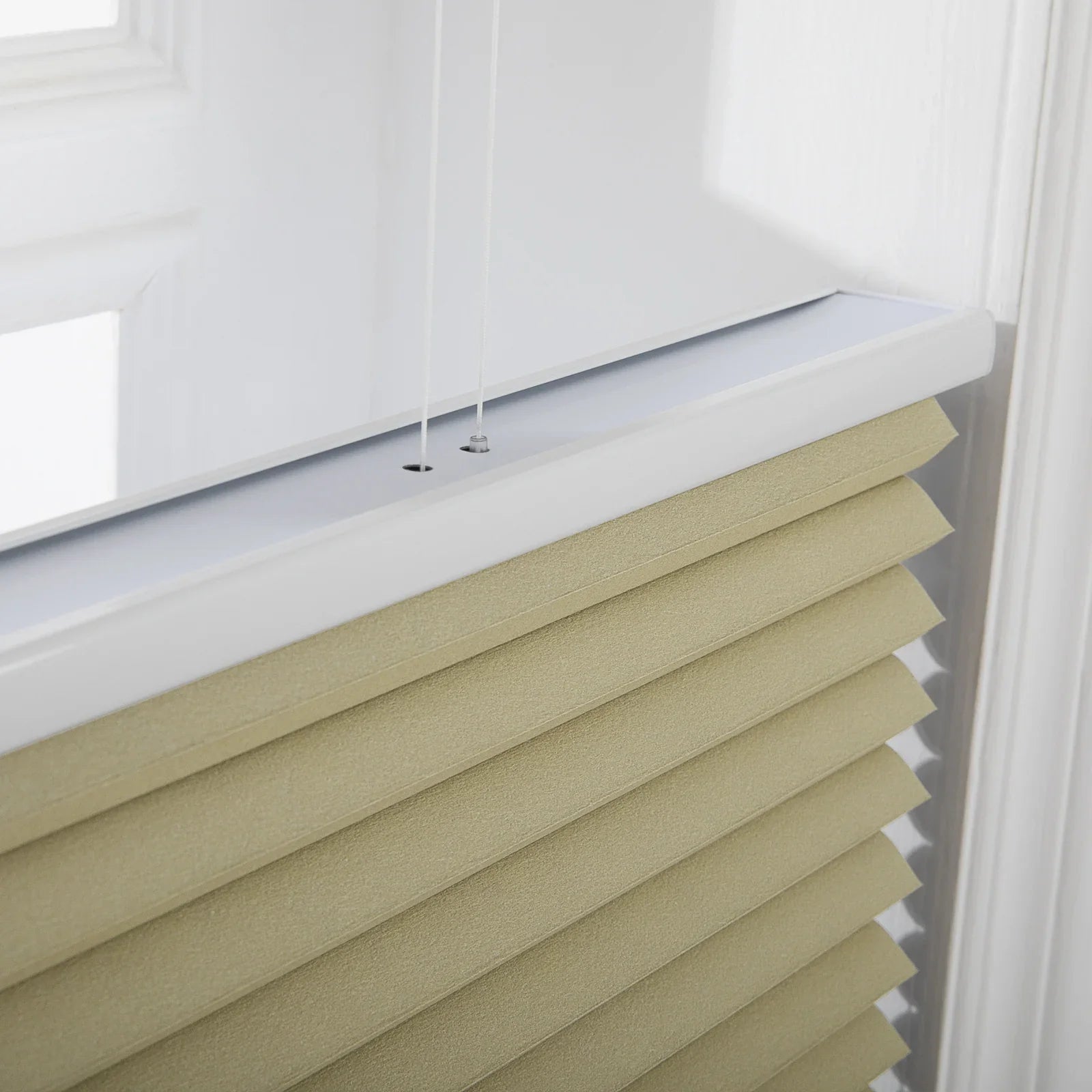 Close-up of sand-colored textured cellular window Blinds featuring a crisp white headrail and two visible thin control strings