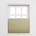 A tan pleated top-down bottom-up cellular Blind covers the lower portion of a white six-pane window with the top half exposed