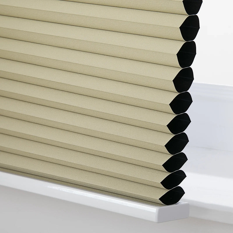 Beige textured cellular Blinds featuring distinct honeycomb pleats with black interior cells resting neatly on a white windowsill