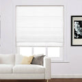 A white Roman blind covering a window in a bright living room, featuring a white sofa with a yellow cushion and a grey patterned cushion, alongside a framed black and white floral art print