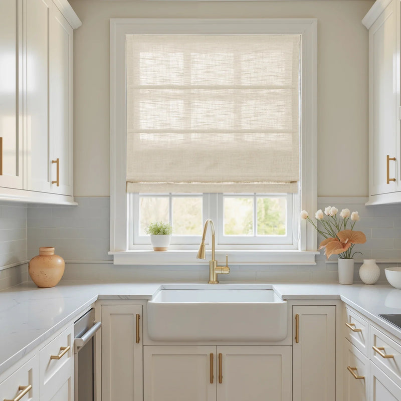 A bright modern kitchen interior featuring a white farmhouse sink, elegant brass gooseneck faucet and matching cabinet hardware, and a light blue subway tile backsplash
