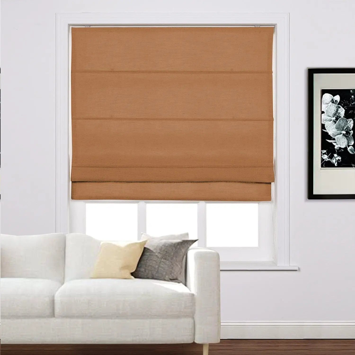 A modern living space showcasing a window dressed with a brown Roman blind, a white sofa featuring yellow and grey accent pillows, and a framed black and white floral artwork