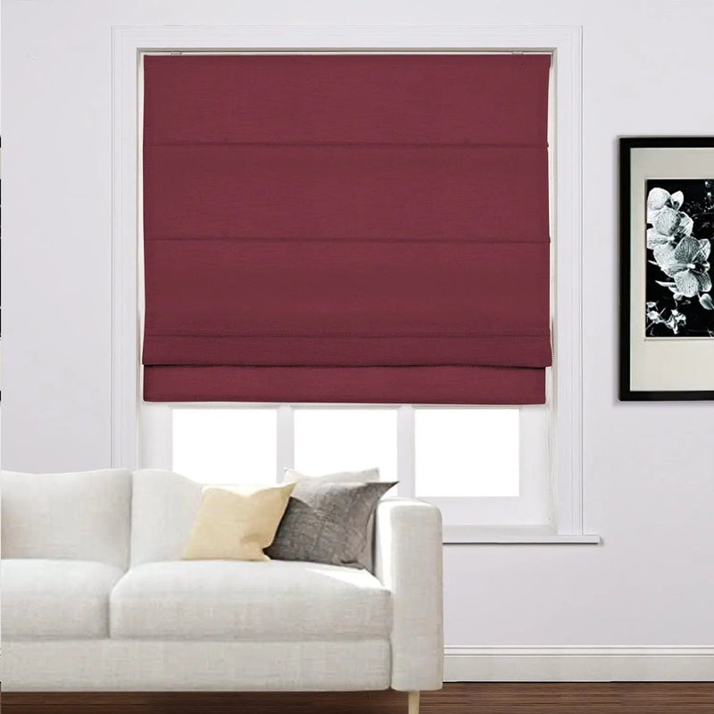 A contemporary interior room featuring a window with a vibrant dark red Roman blind a pristine white sectional sofa with two throw pillows and a black and white floral art print