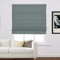 Interior view of a modern living room with a closed teal Roman blind covering a window a white sectional sofa featuring yellow and grey accent pillows and a monochrome floral artwork on the white wall