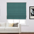 A home interior featuring a window with a teal Roman blind above a white sectional sofa adorned with light yellow and grey pillows and a black and white floral art print on the wall