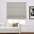 Grey Roman blind covering a white window in a modern living room featuring a white sofa with yellow and grey cushions and a framed black and white floral print on the wall