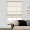A cream semi-sheer Roman blind covers a window in a modern living room featuring a neutral sofa with black and houndstooth pillows and two gold-framed abstract artworks