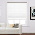 White flat-fold Roman blind covering a window in a modern living room featuring a white two-seater sofa with yellow and grey pillows and a framed black and white floral art print