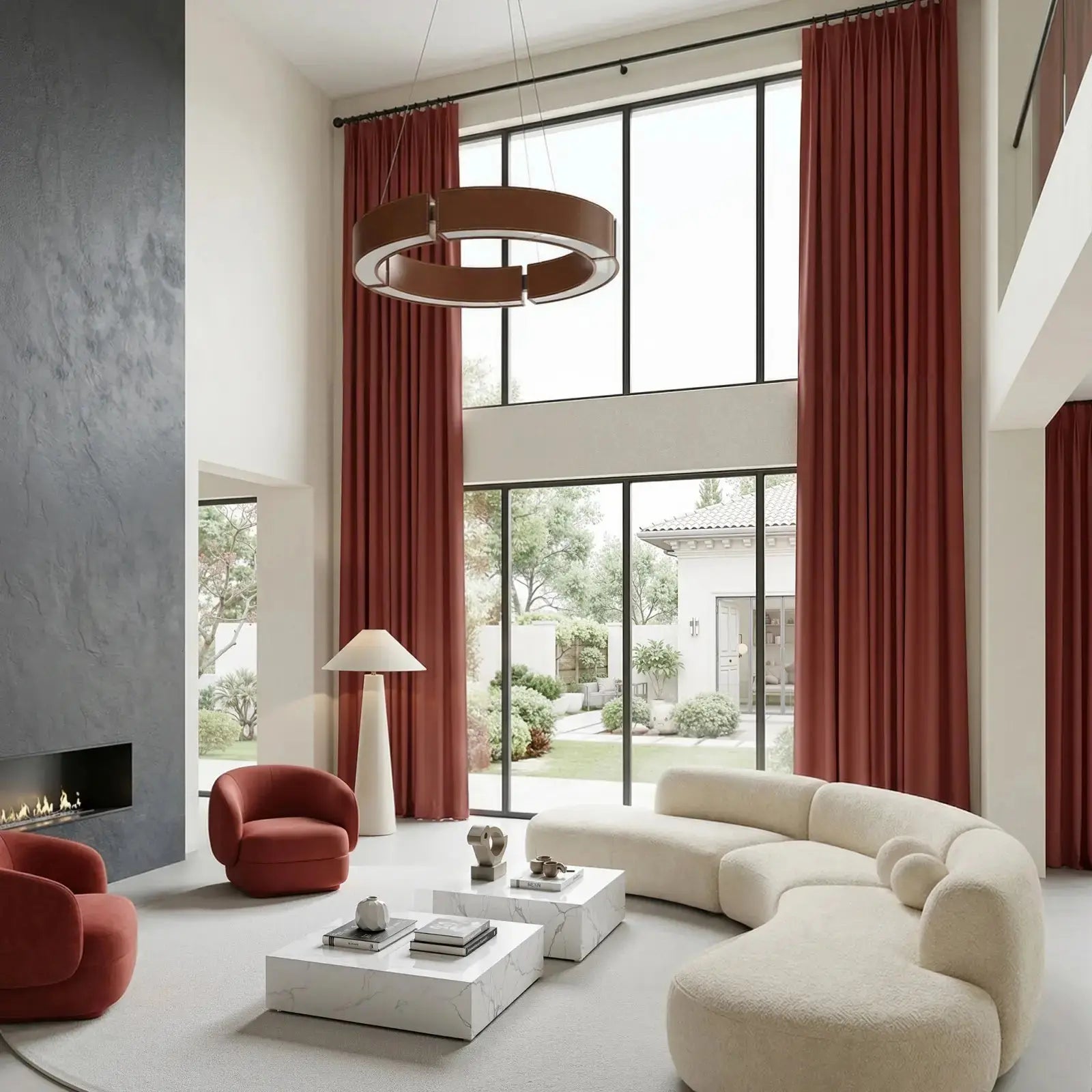 A spacious modern living room with a curved cream boucle sectional sofa, a unique circular brown chandelier, and floor-to-ceiling windows draped in rich terracotta curtains overlooking a lush garden