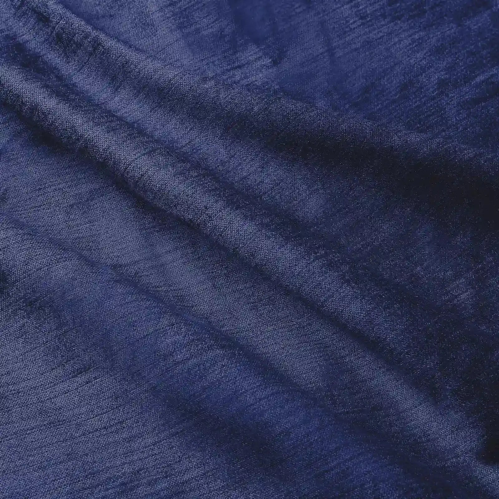 Photograph of rich navy blue textured fabric with flowing folds creating a play of light and shadow across its surface