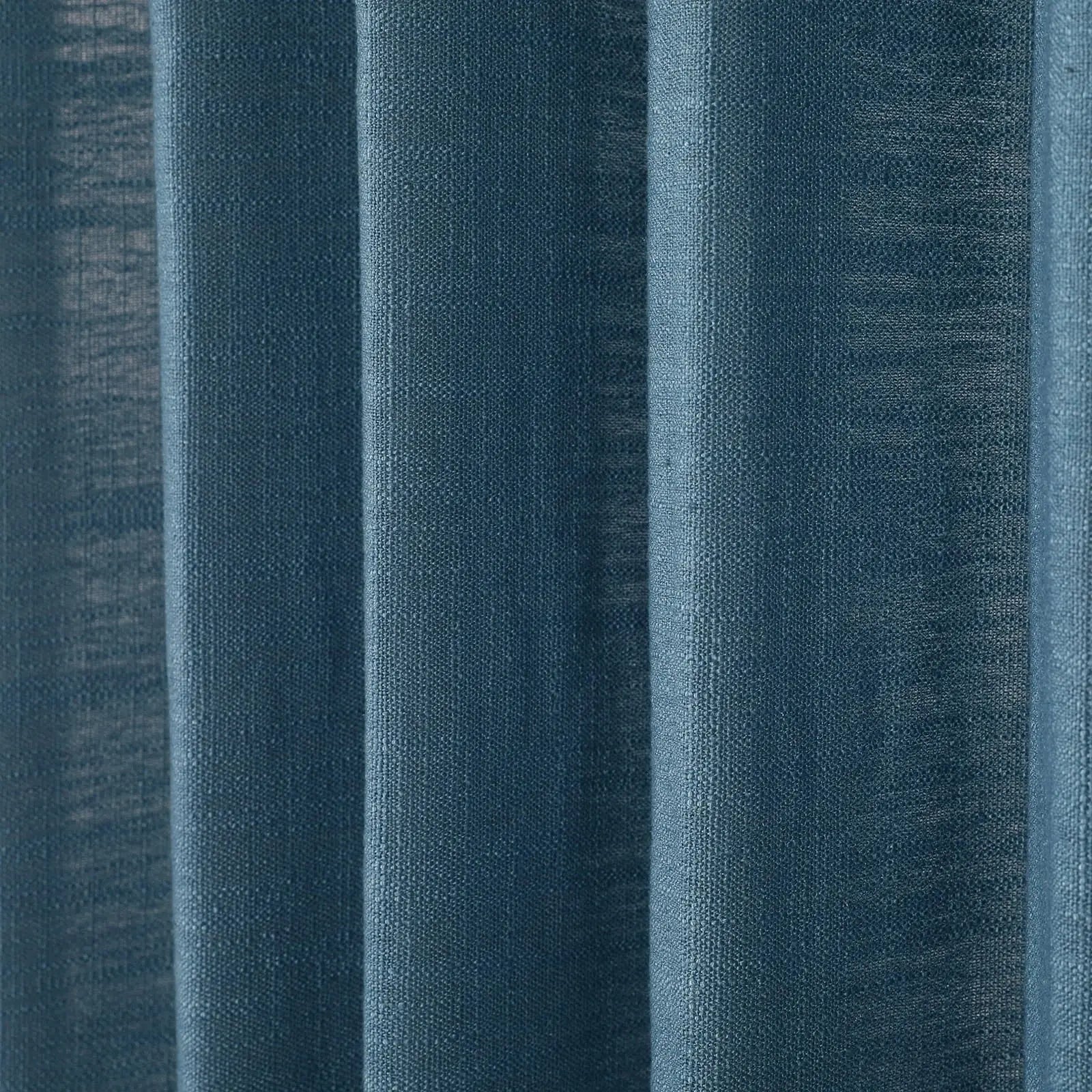 Photograph of deep teal blue woven fabric curtains showing prominent vertical folds and subtle light variations across its textured surface