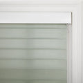 Modern window Blind with alternating sage green opaque and sheer horizontal fabric stripes, framed by white decorative trim and a valance, featuring a control cord