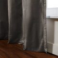 Photograph of a textured charcoal grey curtain panel with subtle sheen draped beside a white window sill, extending to rich brown hardwood flooring