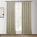 Beige blackout curtains with a black ring top rod frame a white gridded window showing lush green trees