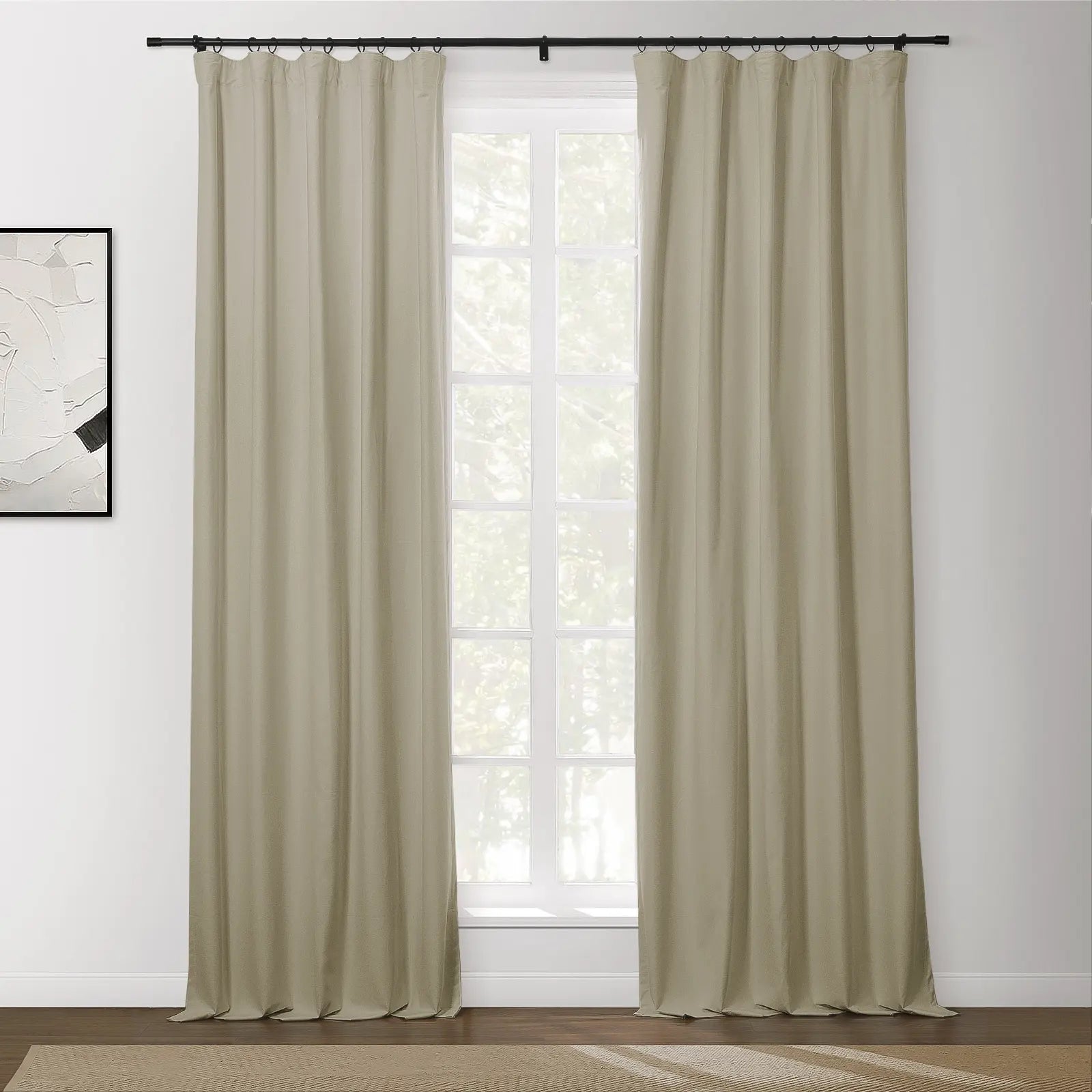 Beige blackout curtains with a black ring top rod frame a white gridded window showing lush green trees