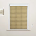 A photograph of an interior window featuring beige horizontal striped dual-layer Blinds set in a white frame with a wall-mounted remote control and a framed botanical print nearby