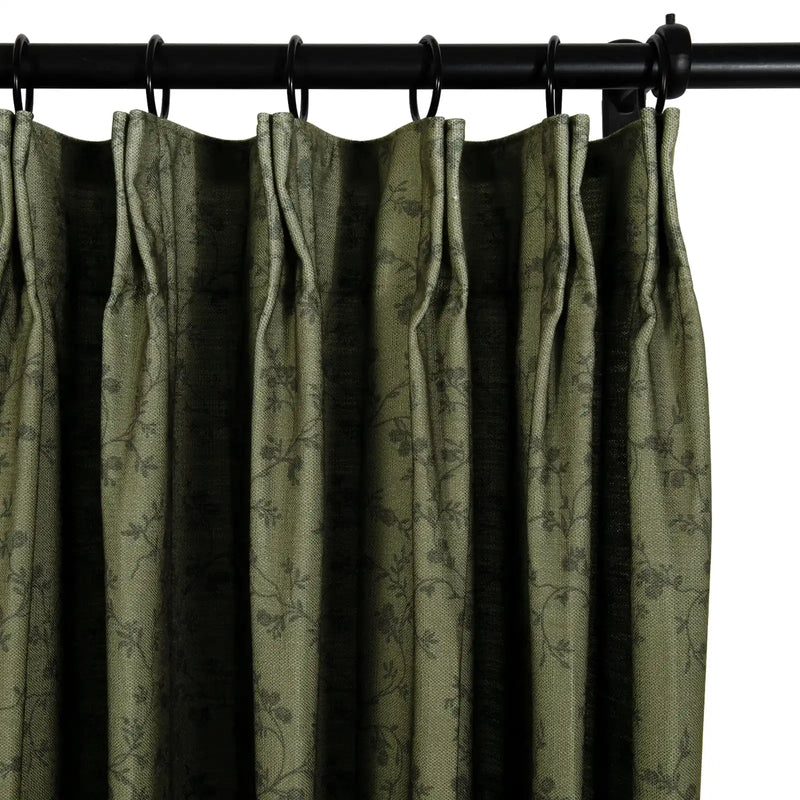 A richly textured olive green curtain panel featuring a subtle dark floral vine pattern suspended from a black metal rod with rings