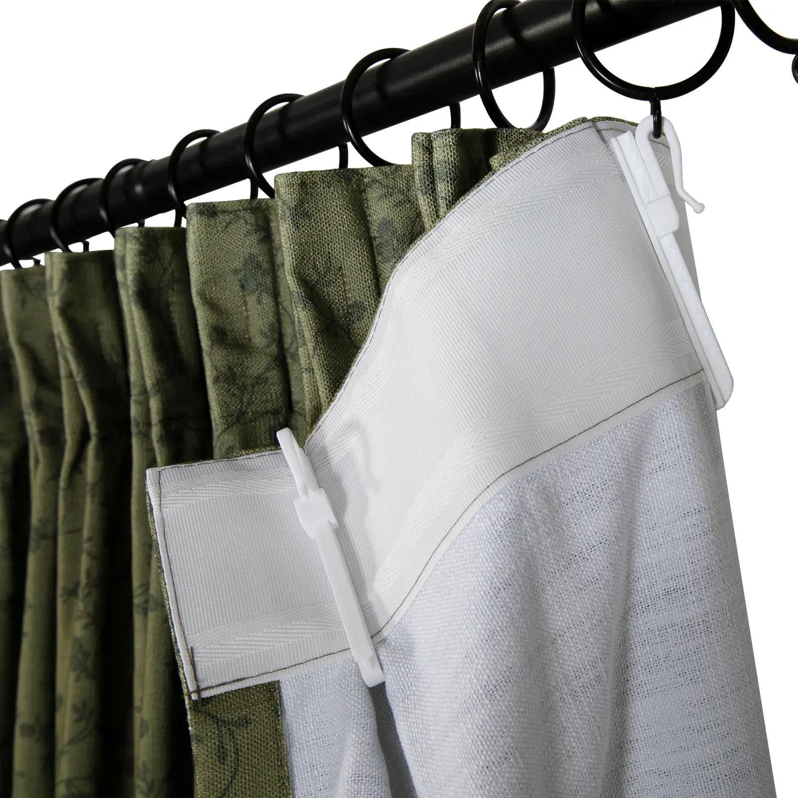 Close-up of olive green pinch pleat curtains featuring a subtle leaf pattern, attached to a black metal rod with rings and white plastic hooks revealing the textured white back-taping