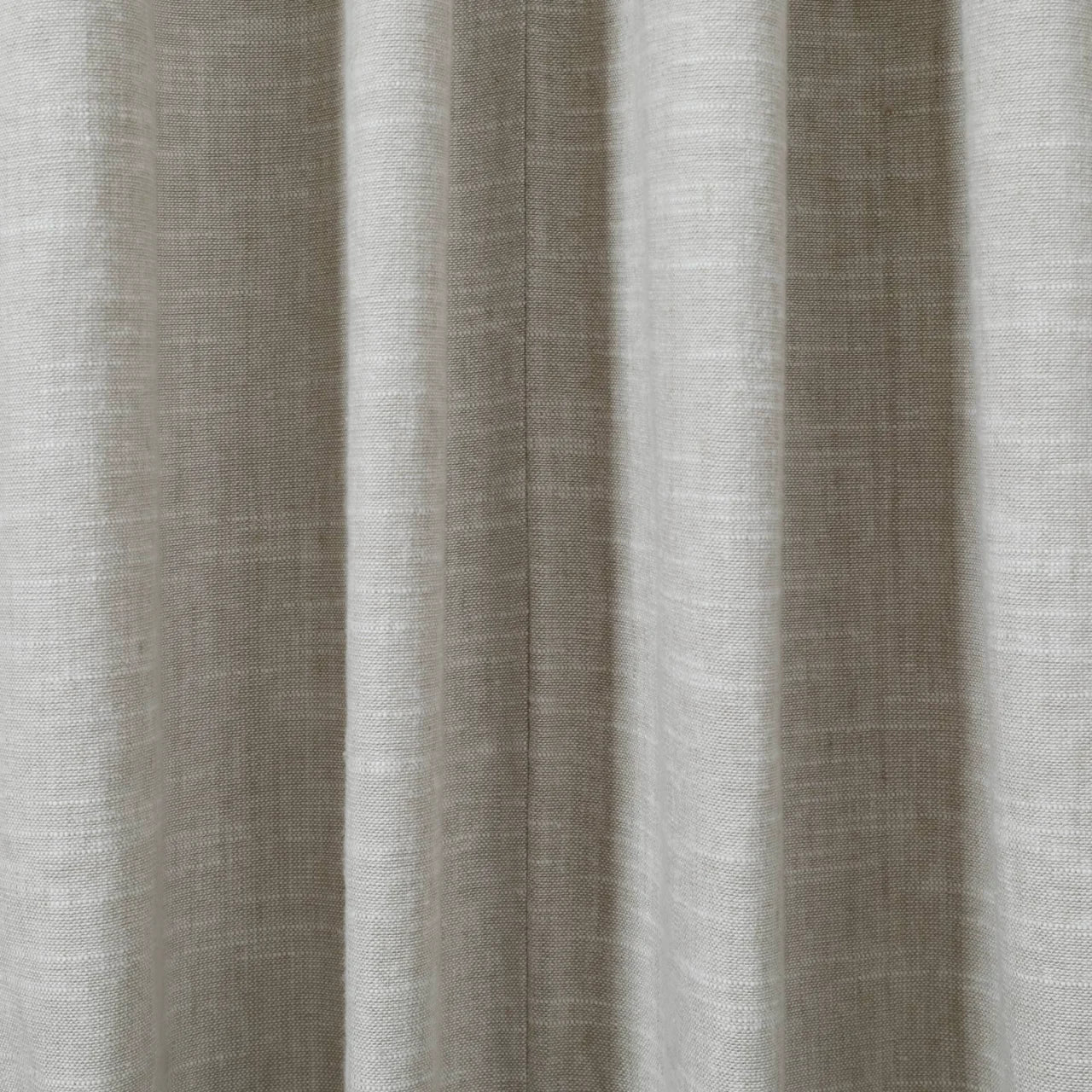 Photograph of light greige textured fabric displaying distinct vertical pleats and a fine central seam