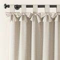 Beige linen-look curtain with decorative tie-top bows hanging from a dark curtain rod