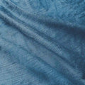 Photograph of deep teal blue textured fabric with soft folds revealing a subtle horizontal weave and luminous indigo hues