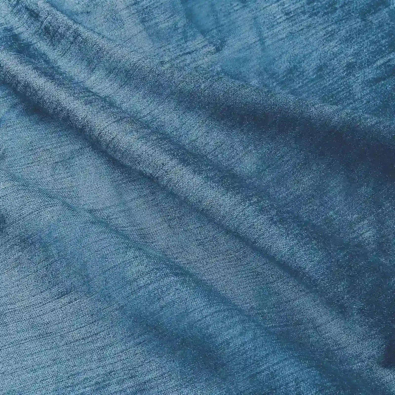 Photograph of deep teal blue textured fabric with soft folds revealing a subtle horizontal weave and luminous indigo hues