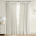 White textured tab-top curtains with decorative bows on a window in a bright room featuring a white three-drawer dresser with brass knobs, a ceramic lamp, and a framed botanical print