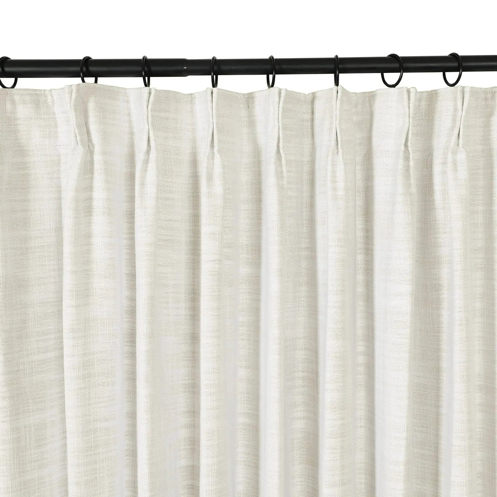 A close-up view of an off-white textured linen curtain with a pleated top hanging from a black metal rod with black rings