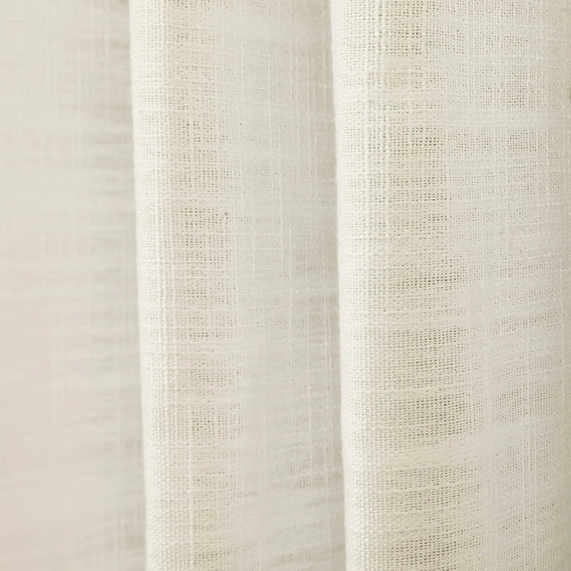 Digital Photograph of a cream-colored linen-like fabric curtain featuring a coarse open weave and gentle vertical folds