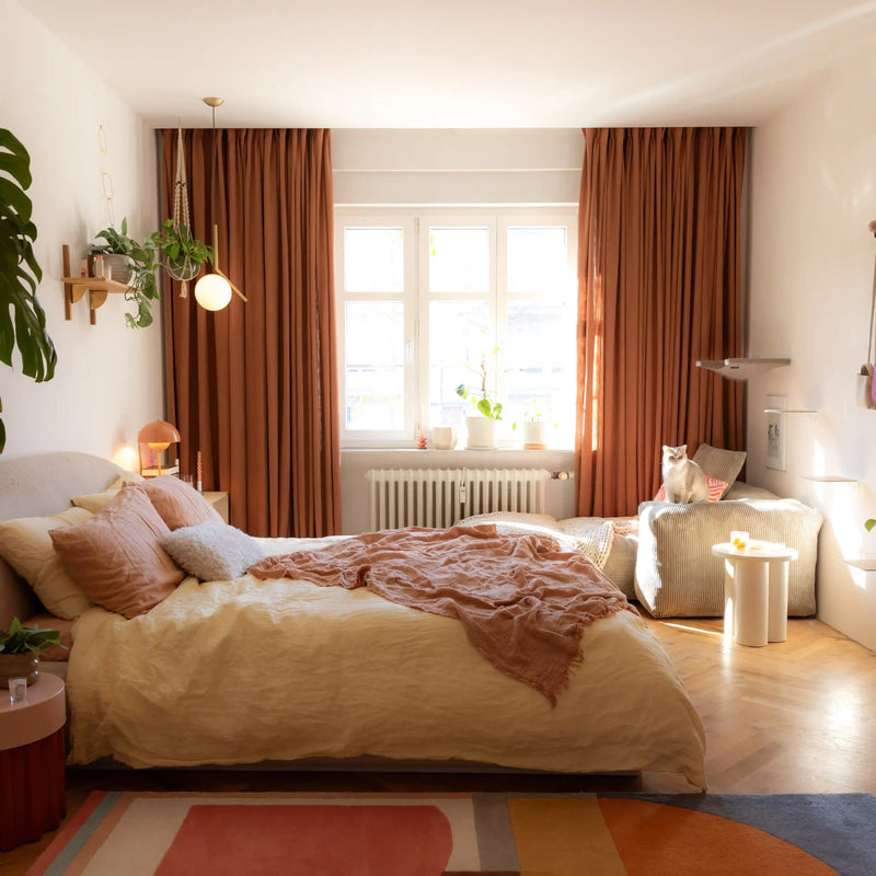 Orange Copper Liz linen curtains viewed at an angle in a softly styled room with natural daylight