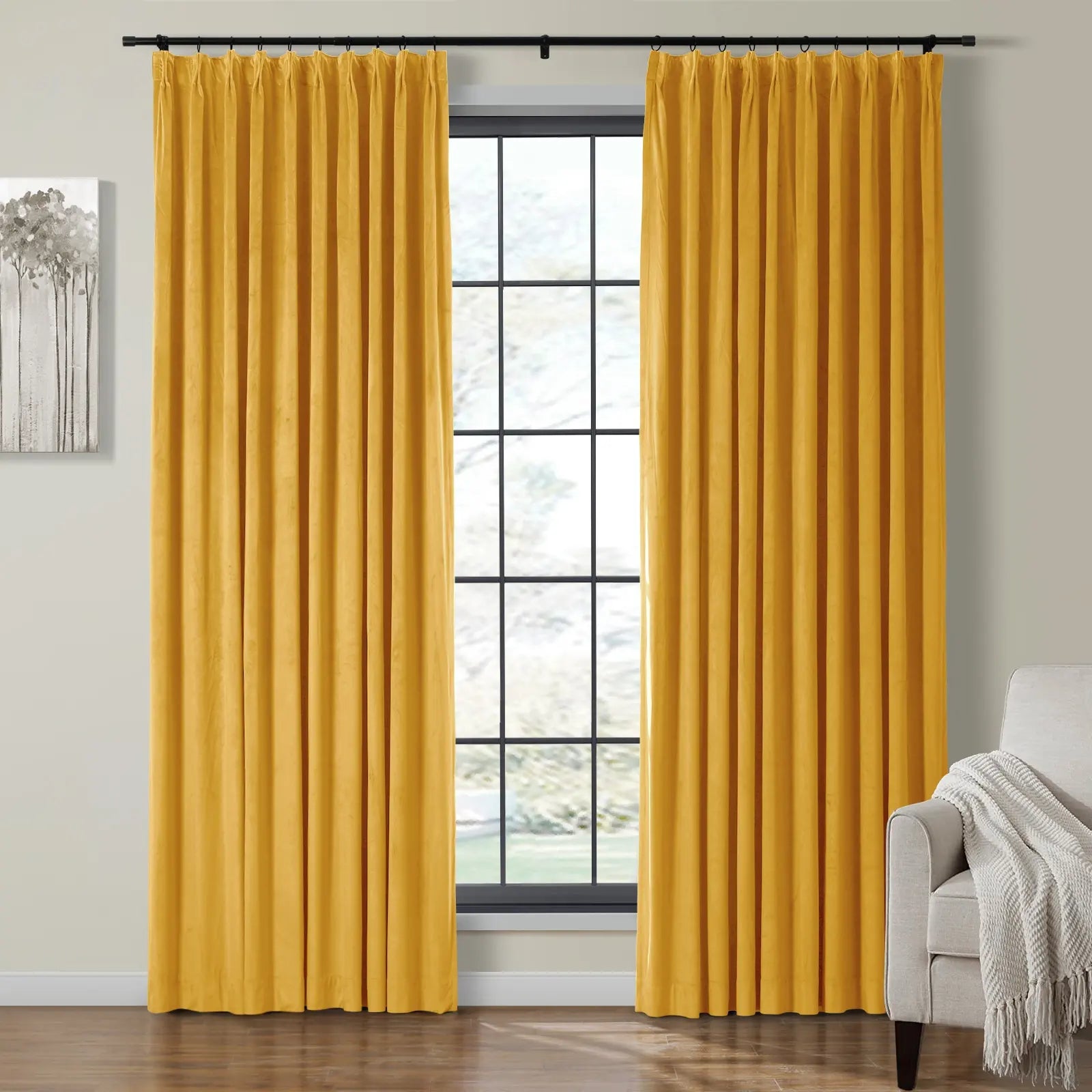 A cozy living room features rich mustard yellow velvet curtains framing a black grid-pane window, beside a light gray armchair with a white fringed throw blanket and minimalist monochromatic tree artwork on the wall