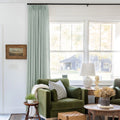 Pale Blue Aqua Liz linen curtains shown closer beside a sunlit window with smooth vertical folds