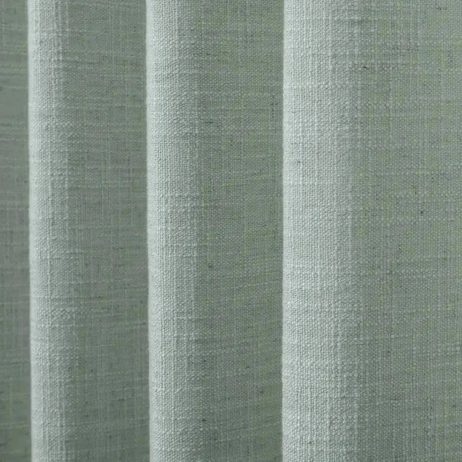 Textile featuring light sage green woven fabric with a distinct slubby texture arranged in soft vertical pleats