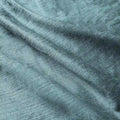 Close-up photograph of a muted teal blue-green textile showcasing its visible textured weave and soft, curving folds catching the light