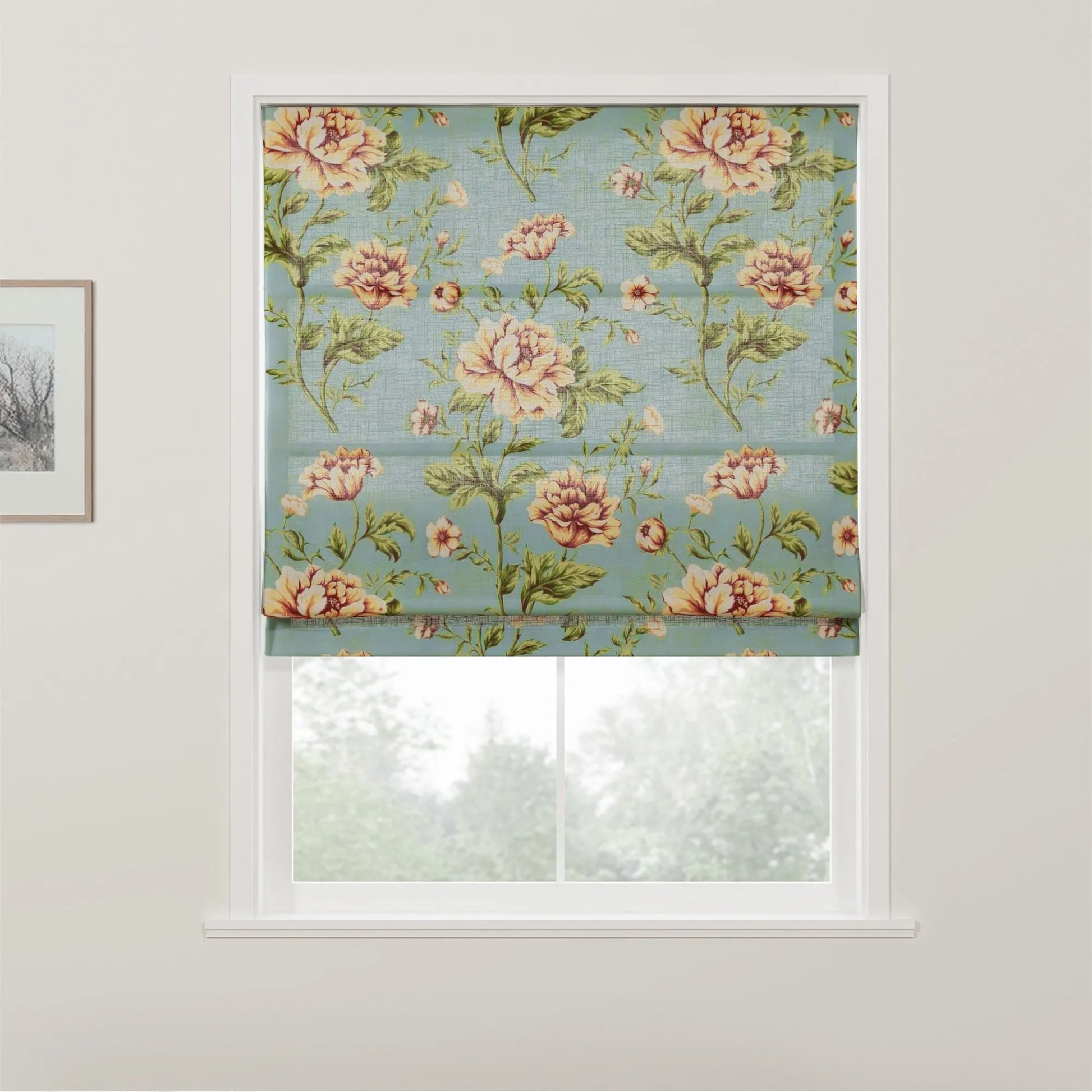 Fabric roman blind featuring a vintage floral pattern with large peach and yellow roses and green leaves on a teal blue background, partially covering a white window with a view of trees