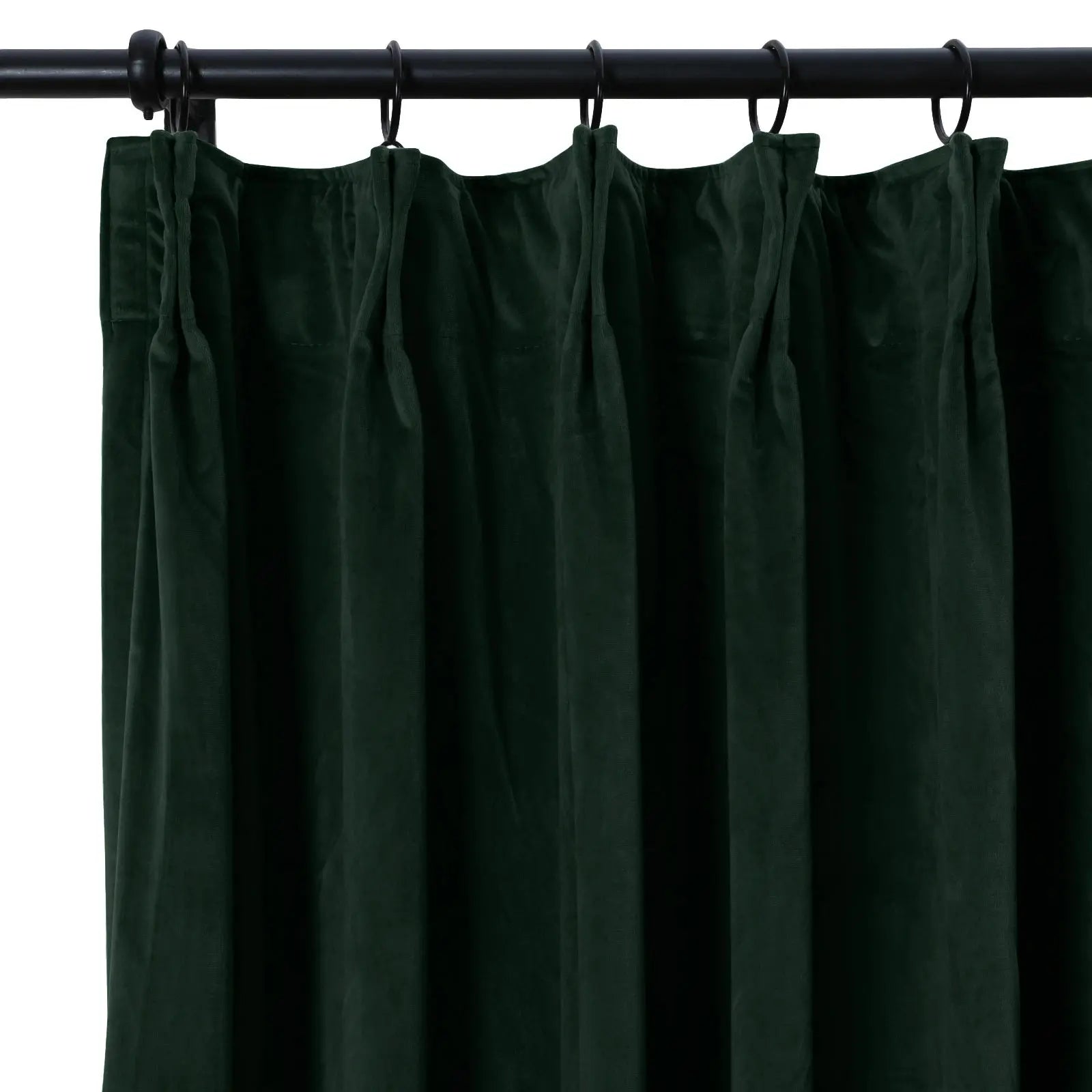 Forest green velvet curtain with lush pleated texture hanging from a black metal rod with rings