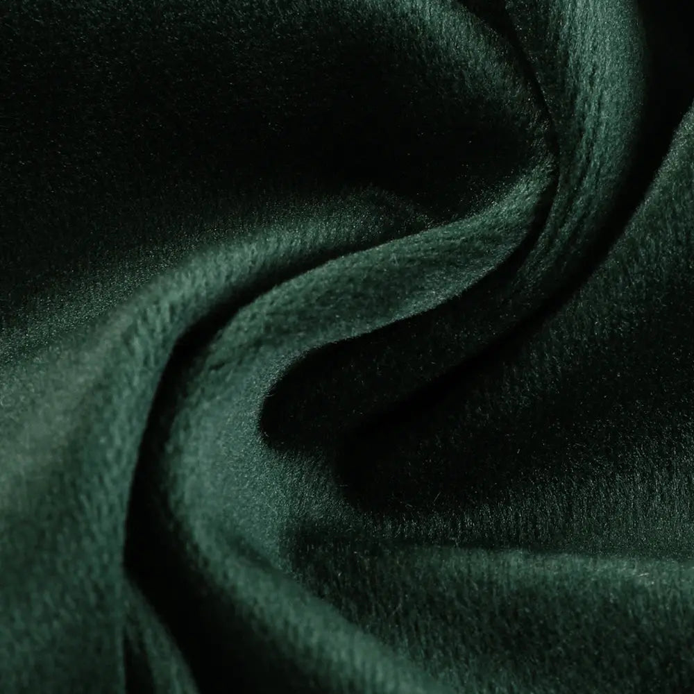 Emerald green plush fabric featuring a rich velvety texture and dynamic folds illuminated by soft highlights and shadows