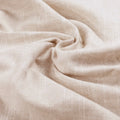 Close-up photograph of natural light beige woven fabric with a distinct textured surface and soft, flowing folds creating a subtle spiral pattern