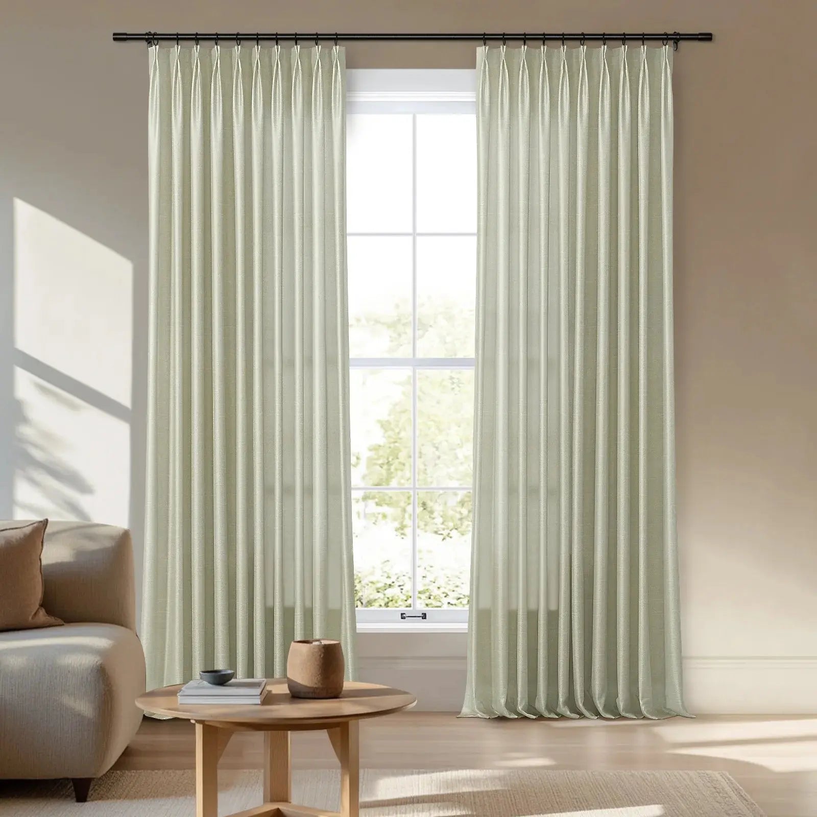Digital photograph of elegant pale green pleated curtains on a black rod, framing a bright window in a modern minimalist living room featuring a beige sofa and a light wooden coffee table