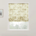 Photograph of an interior window featuring a textured cream Roman blind adorned with a subtle muted green and brown botanical pattern, partially raised to reveal a blurred view of lush green trees outside