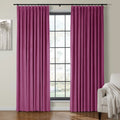Photograph of a living room interior with vibrant magenta velvet curtains framing a multi-paned window, beside a grayscale tree painting and a beige armchair draped with a textured throw