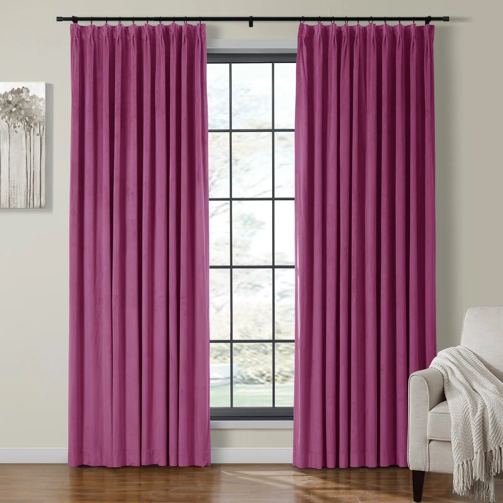 Photograph of a living room interior with vibrant magenta velvet curtains framing a multi-paned window, beside a grayscale tree painting and a beige armchair draped with a textured throw