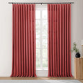 Faux silk rich rust-red pleated curtains on a black rod frame a sunlit window revealing green trees, accented by a fluted wood table with a black vase and gold candlestick