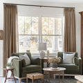 Rust Brown Liz Linen Pleated Curtains framing a green sofa beneath a wide sunlit window