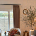 Rust Brown Liz Linen Pleated Curtains in a warm reading nook with an armchair, wall clock and olive tree